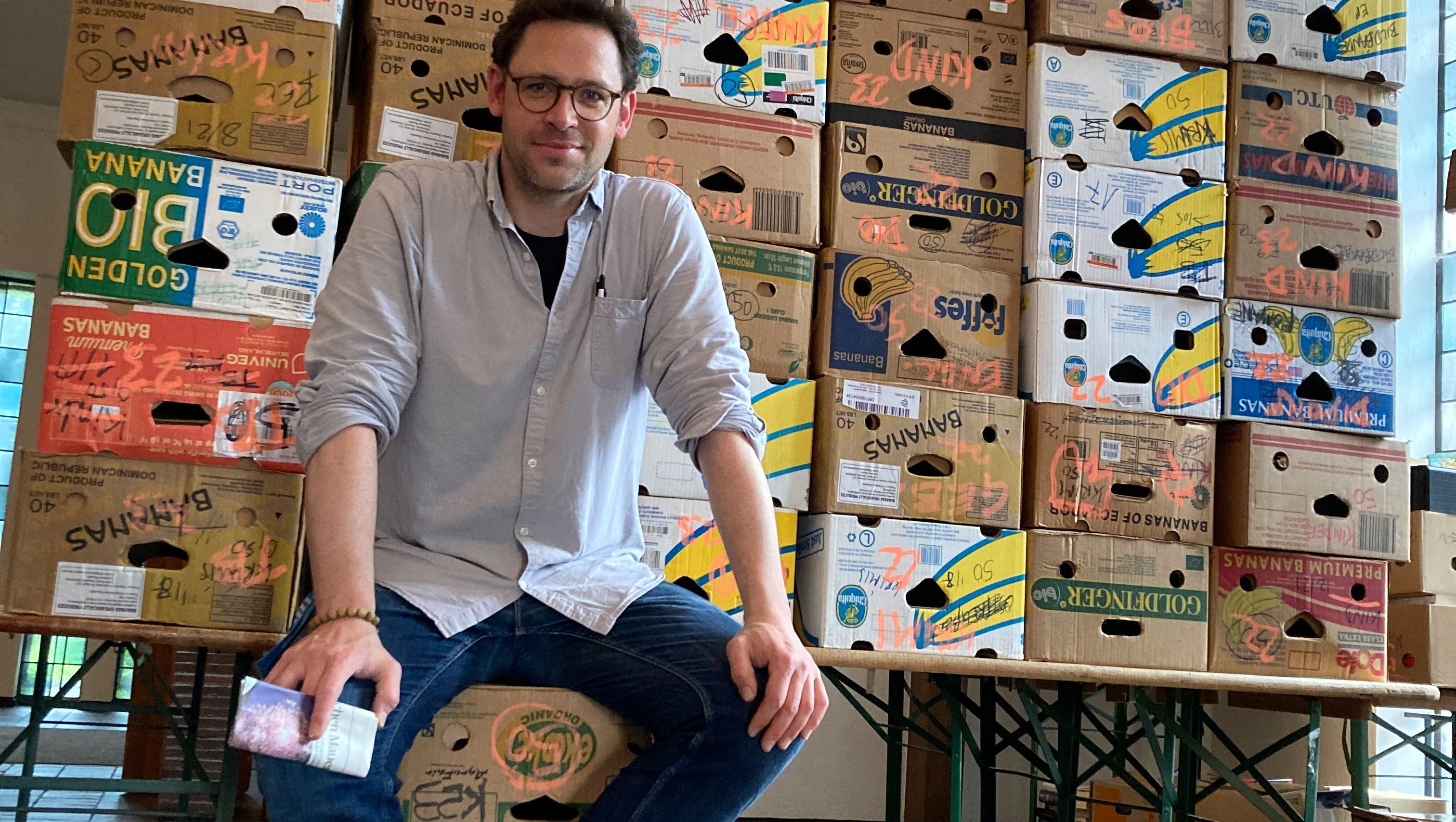 Ehrenamtlicher Lars Terlinden mit Kartons für den nächsten Buchmarkt
